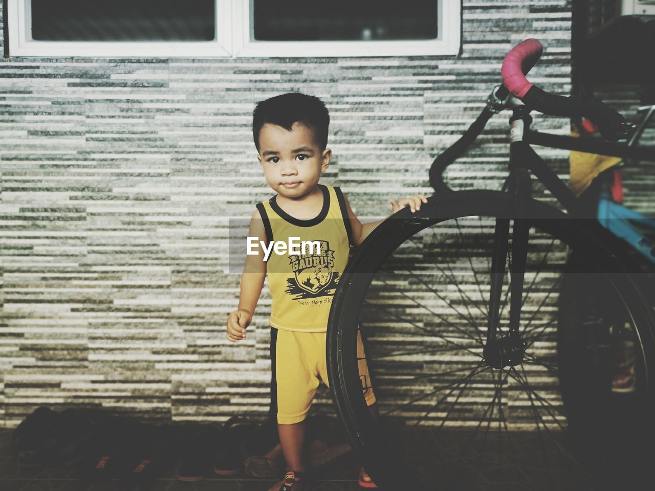 PORTRAIT OF BOY STANDING AGAINST BRICK WALL