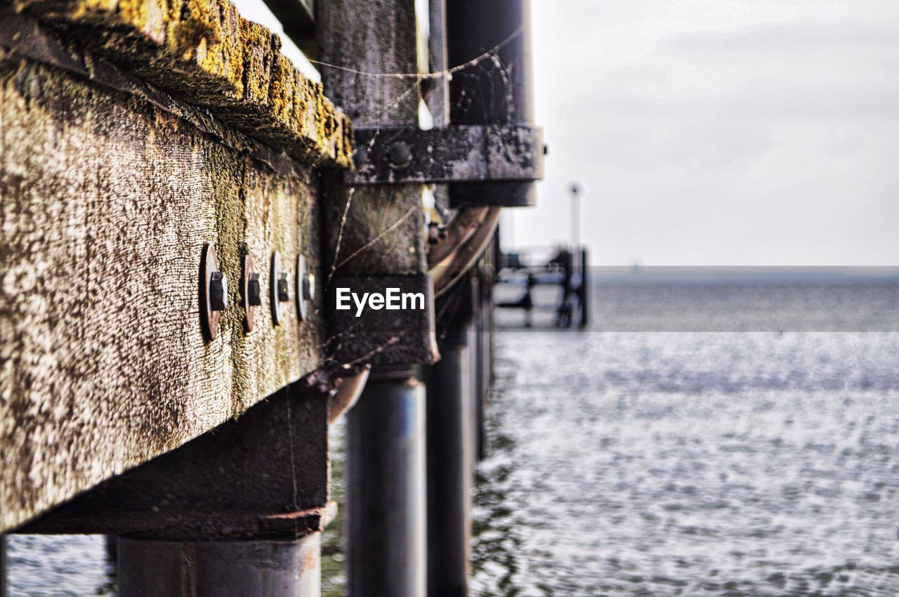 Close-up of wooden post by sea against sky