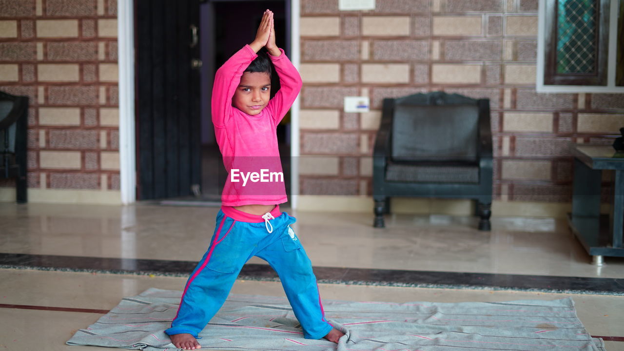  little indian boy doing yoga exercise and watching instructions on tv.. worldwide yoga day concept.