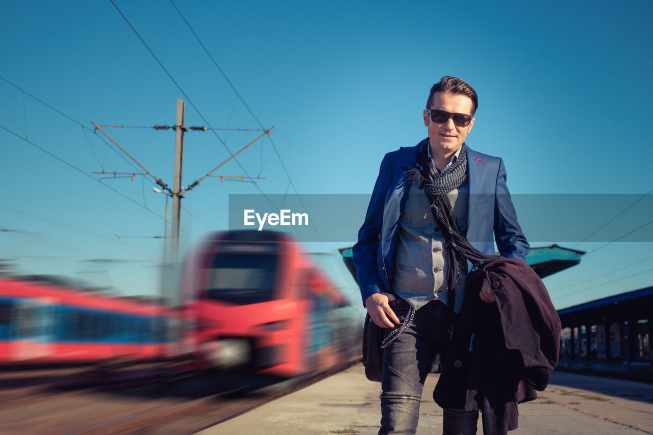 Portrait of smiling handsome man standing at railroad station platform