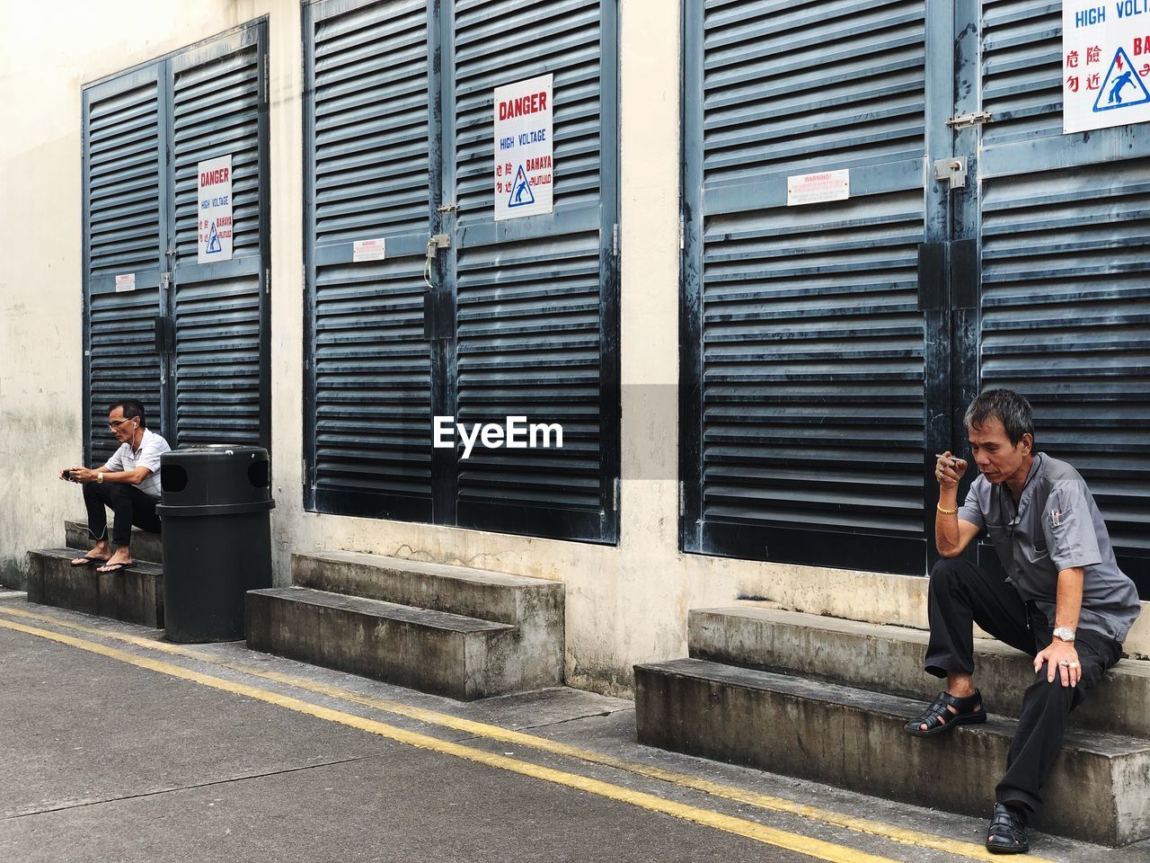 Two men sitting by buildings in city