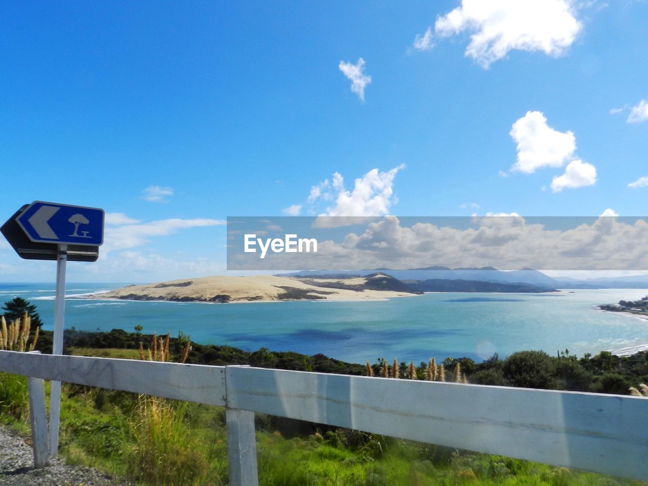 Road sign by sea against sky