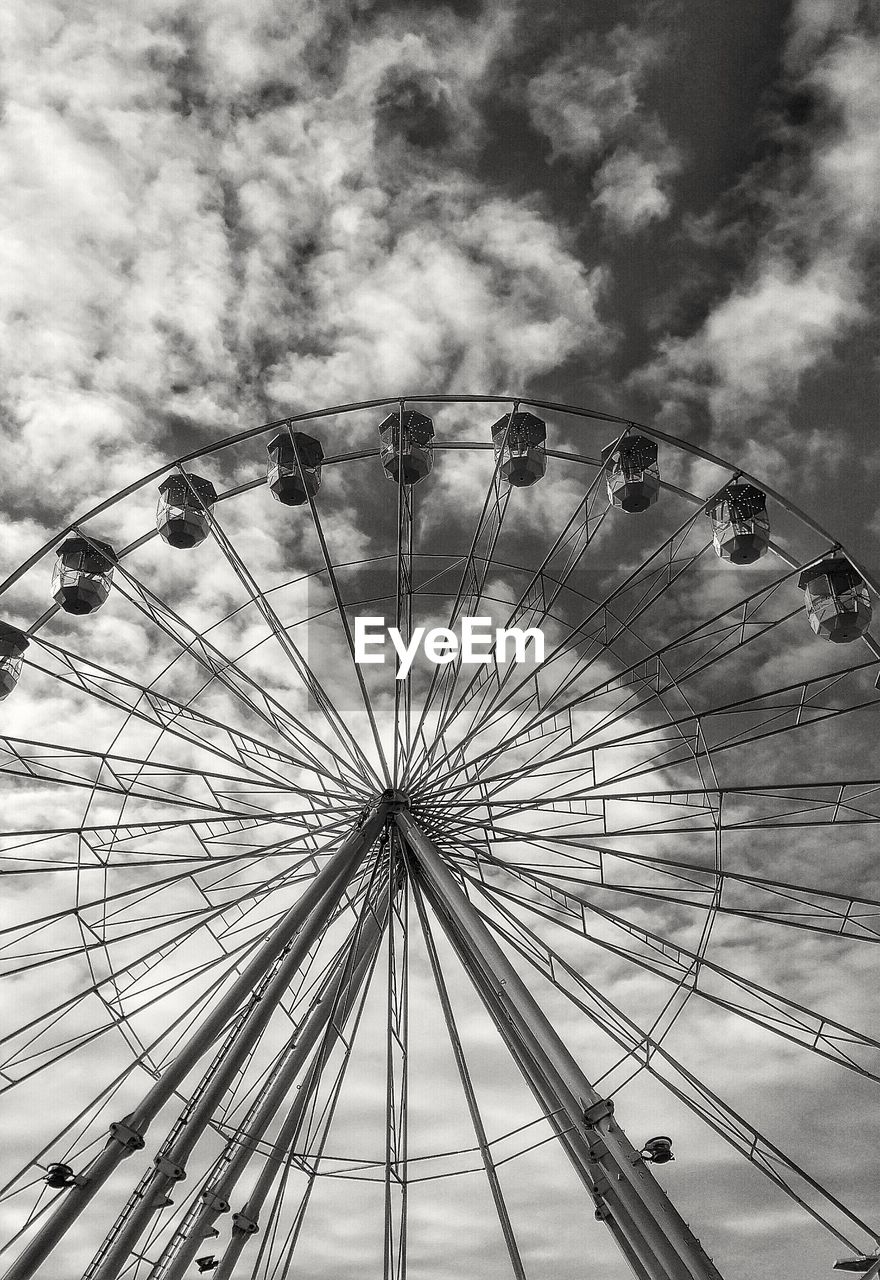 Low angle view of ferris wheel against cloudy sky