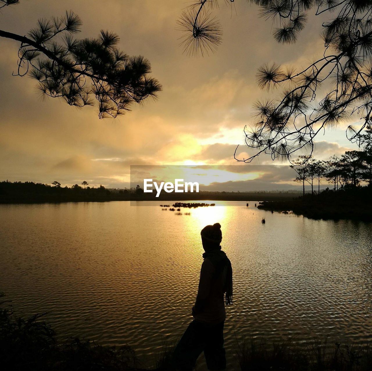 SILHOUETTE MAN STANDING ON LAKE AGAINST SKY DURING SUNSET