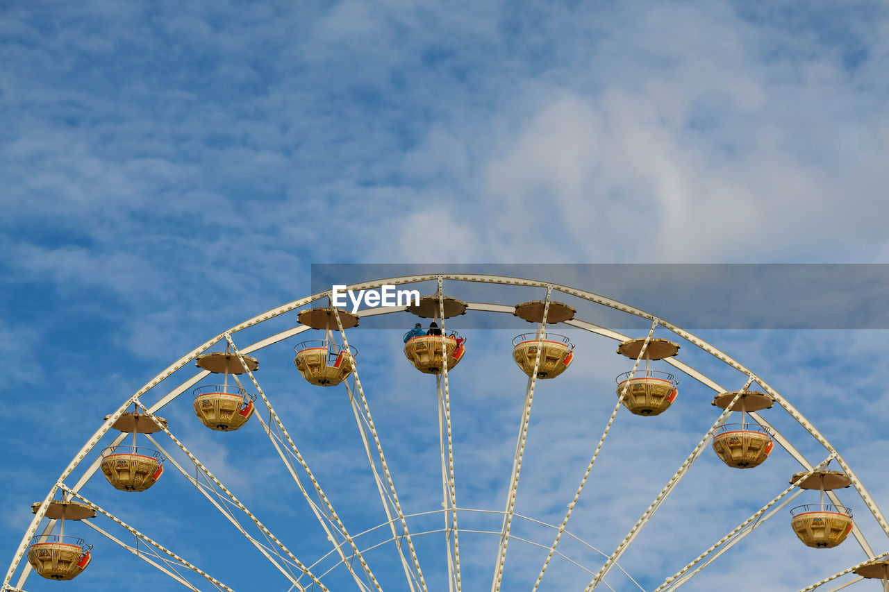 Low angle view of ferris wheel against blue sky during sunny day