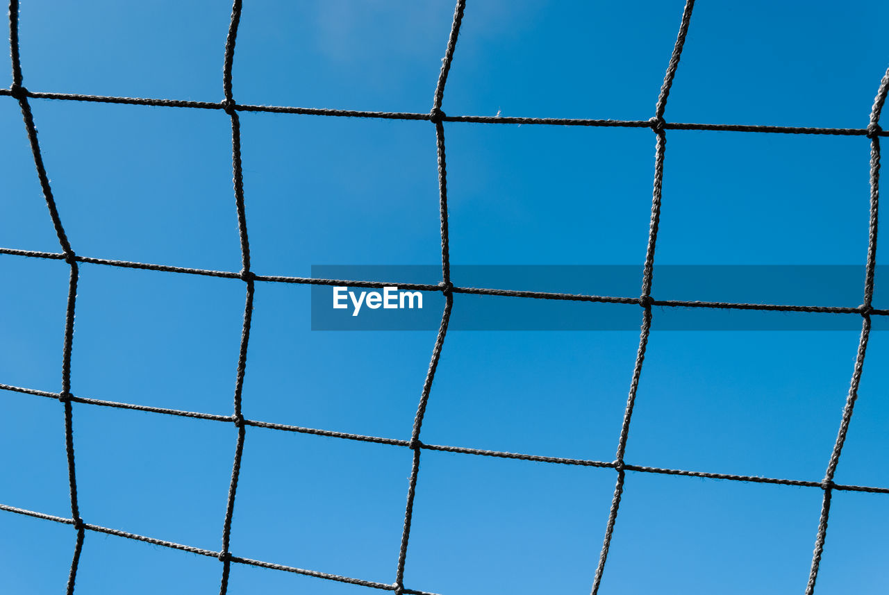 Low angle view of blue sky seen through fence