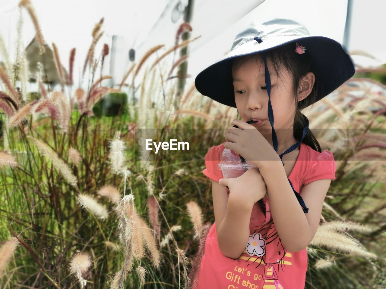 Close-up of girl having drink while standing by plants