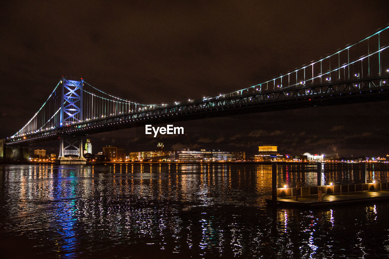 Illuminated bridge over river at night