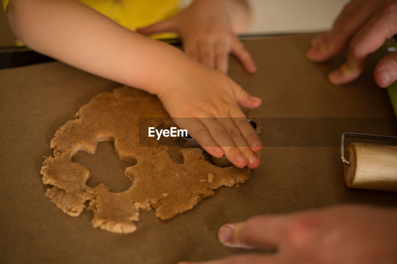 Cropped hands of girl preparing cookie at table