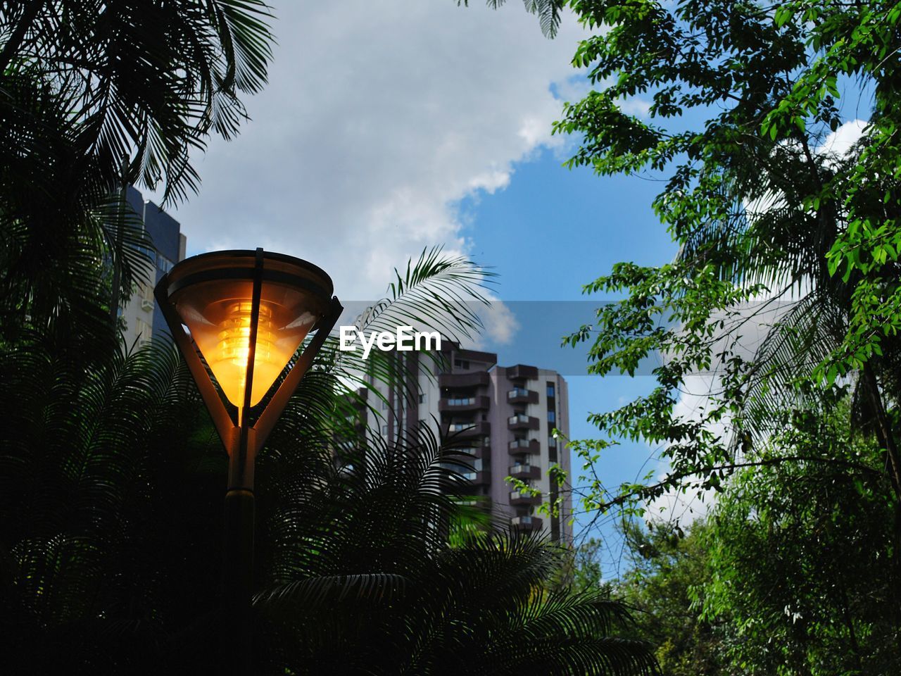 Low angle view of illuminated street light against cloudy sky