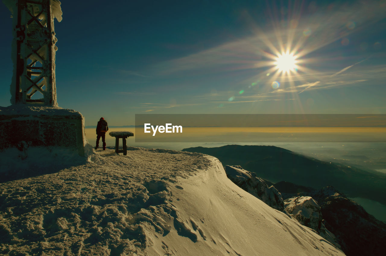 MAN ON SNOW COVERED LAND AGAINST SKY