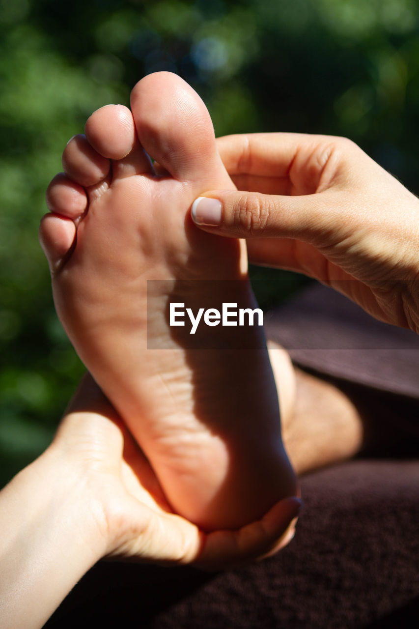 Cropped hands of massage therapist massaging customer leg at spa