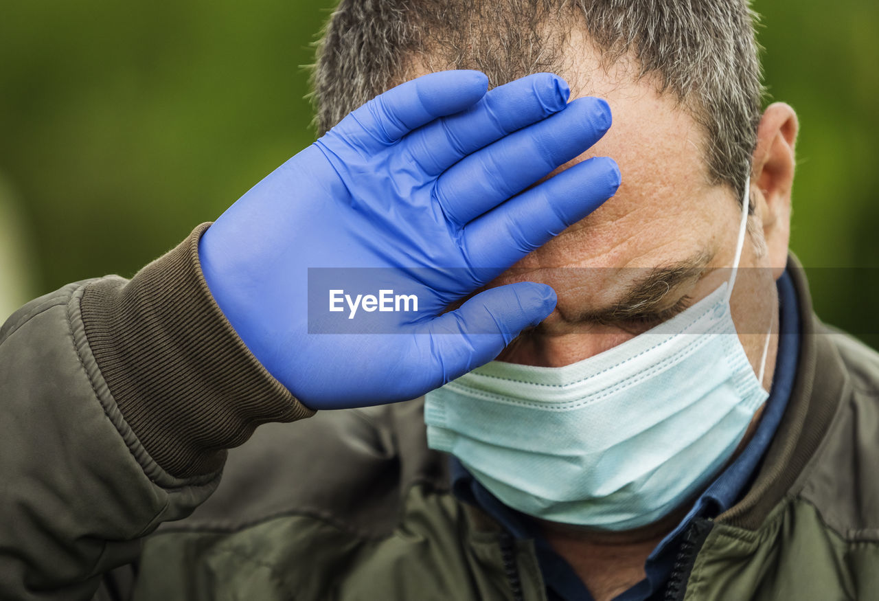 Adult man in a medical mask. he has a headache and a high fever. coronavirus concept