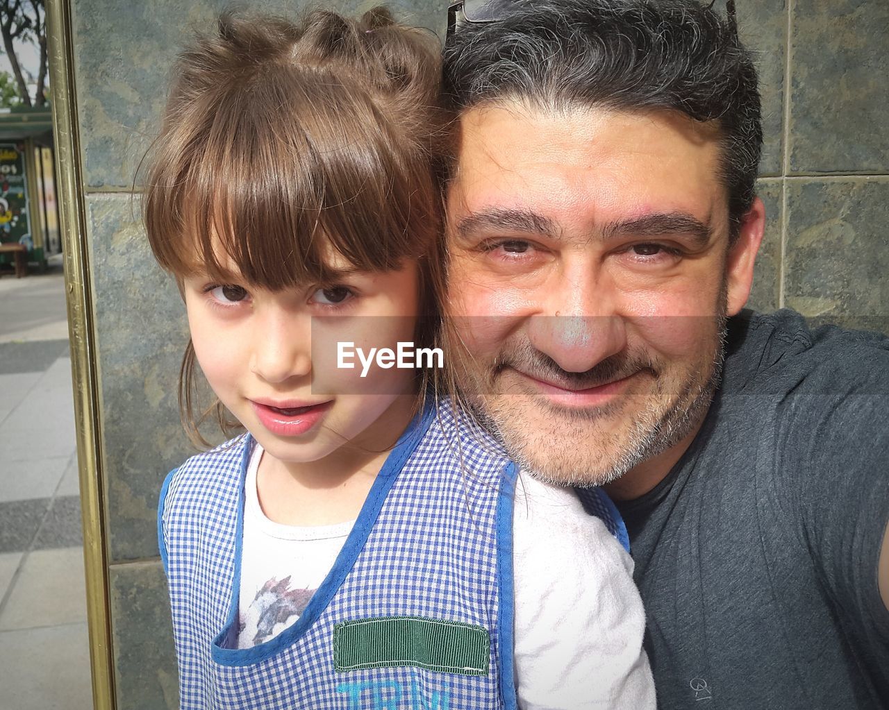 Portrait of happy father and daughter against wall