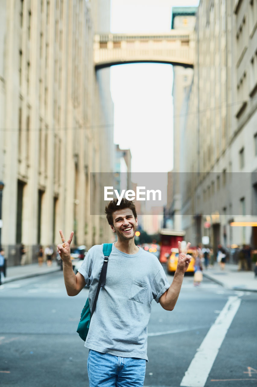 Young man gesturing peace sign while standing in city