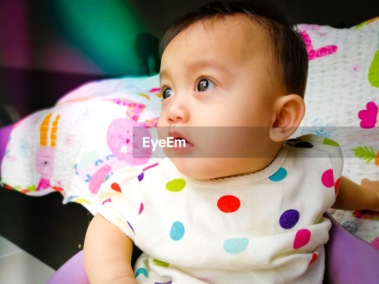 Close-up of cute baby girl sitting on chair at home