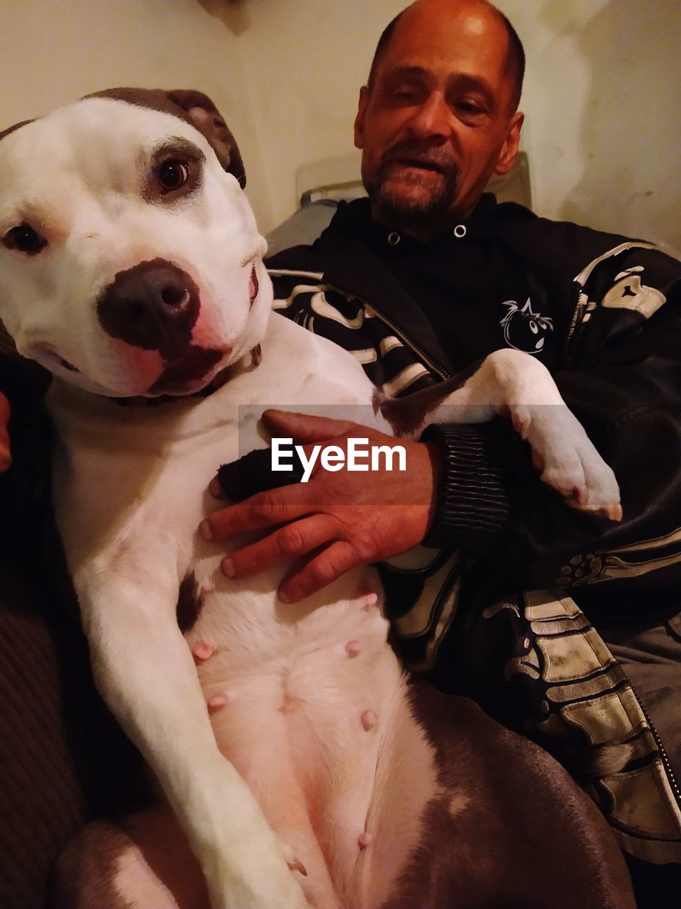 PORTRAIT OF A MAN WITH DOG AT HOME