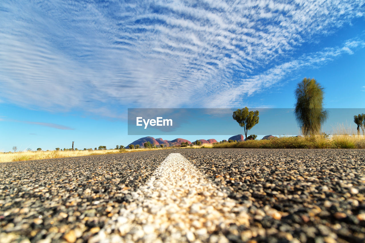 SURFACE LEVEL VIEW OF PEBBLE ROAD AGAINST SKY