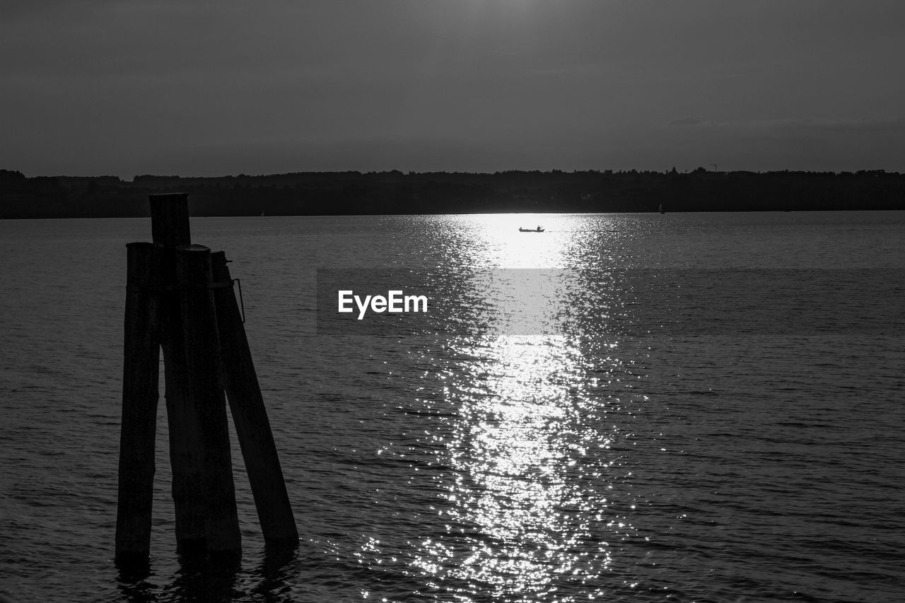 WOODEN POSTS IN LAKE AGAINST SKY