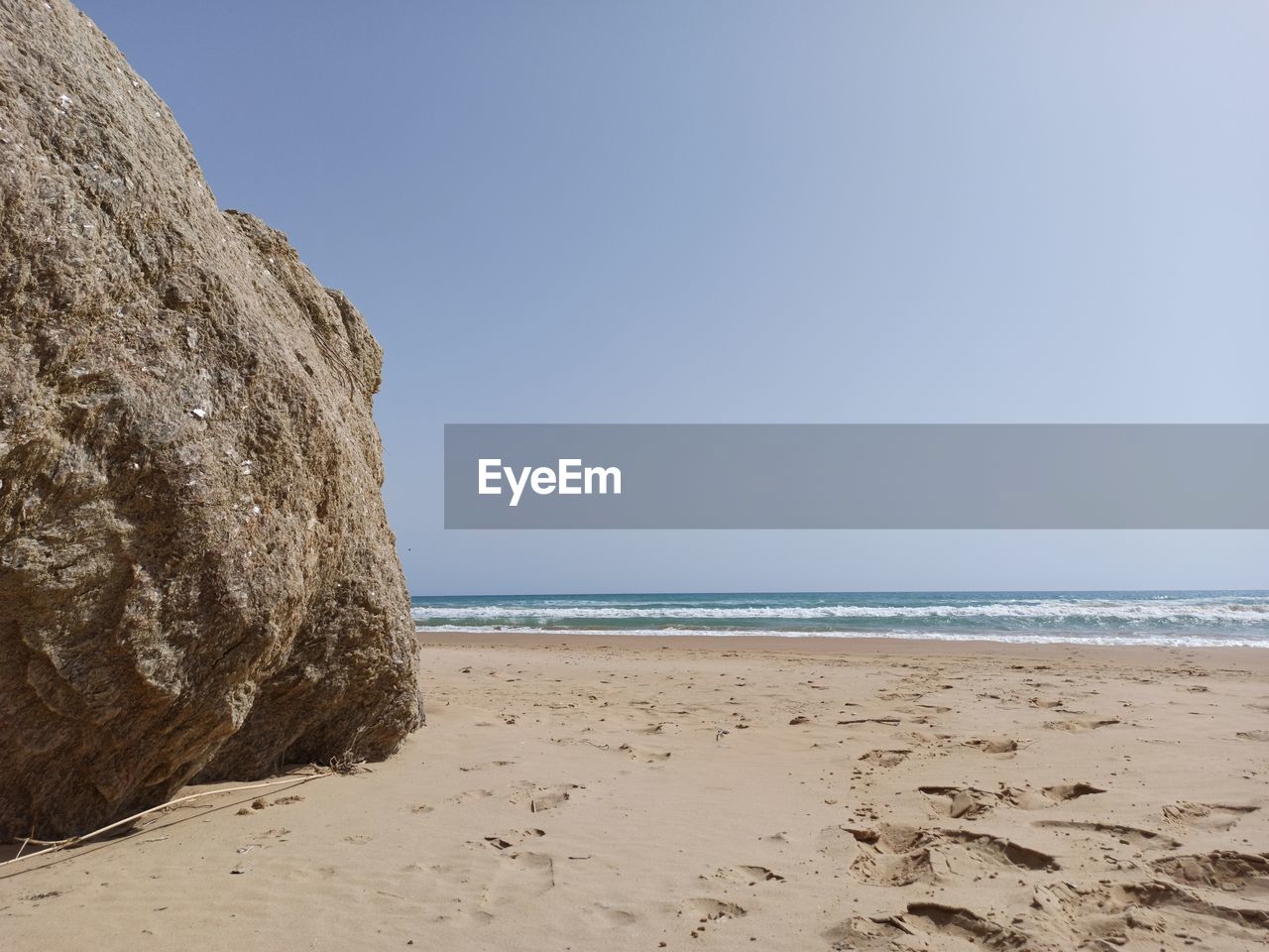 ROCK FORMATIONS ON BEACH AGAINST CLEAR SKY