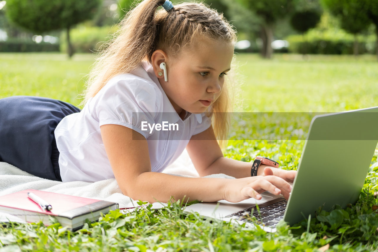 side view of boy using laptop at park