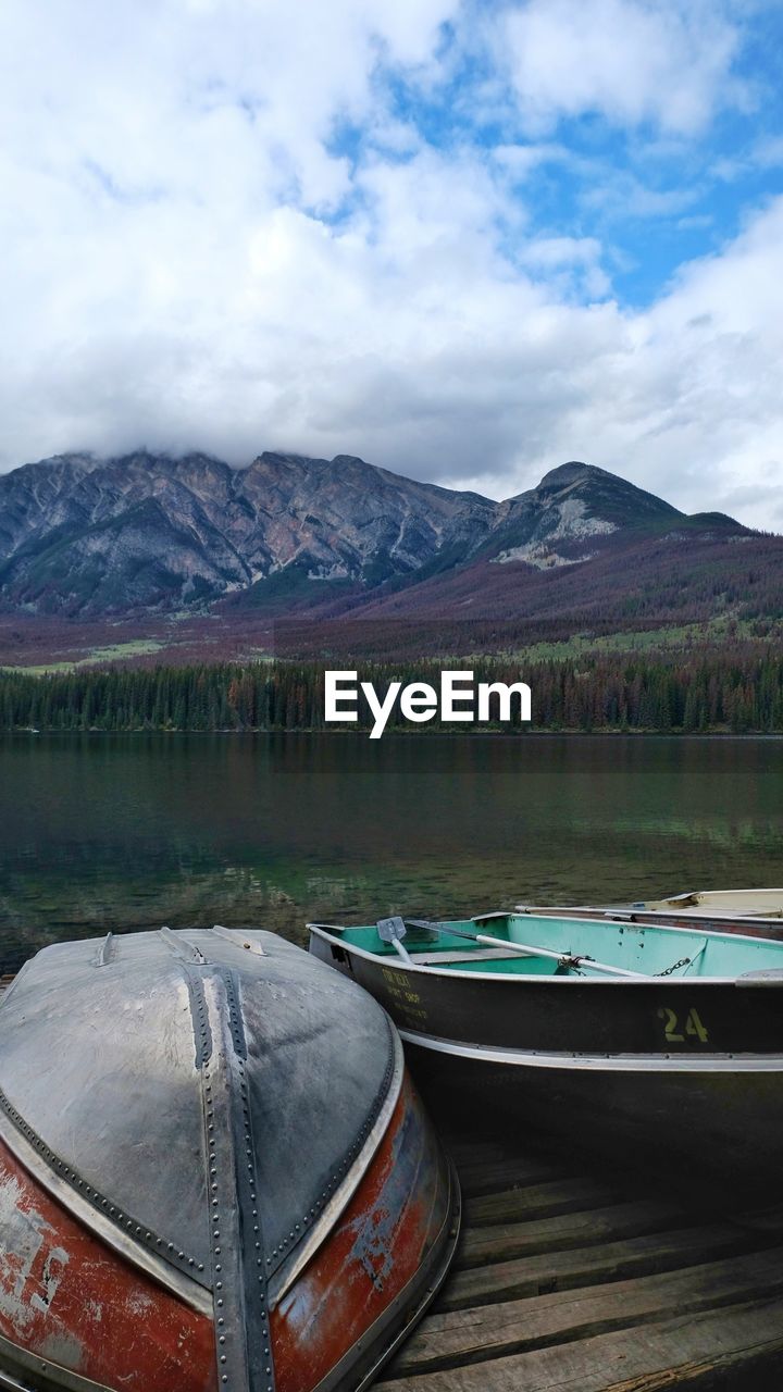 BOATS MOORED BY LAKE AGAINST SKY