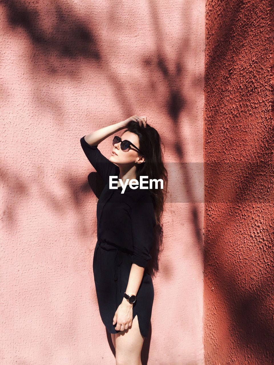 Woman standing against pink wall