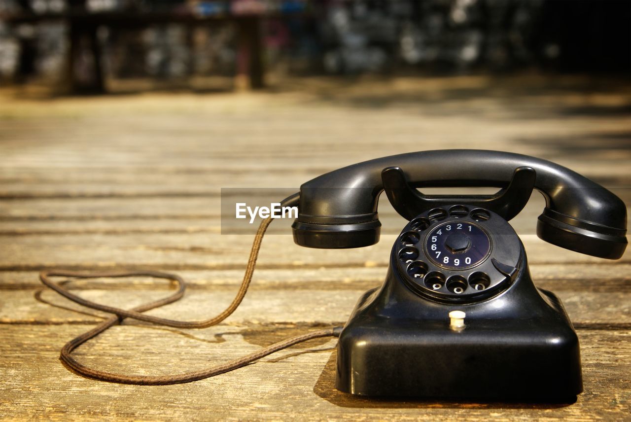 Close-up of black rotary phone on wooden floor