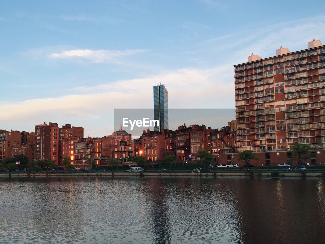 City at waterfront against cloudy sky