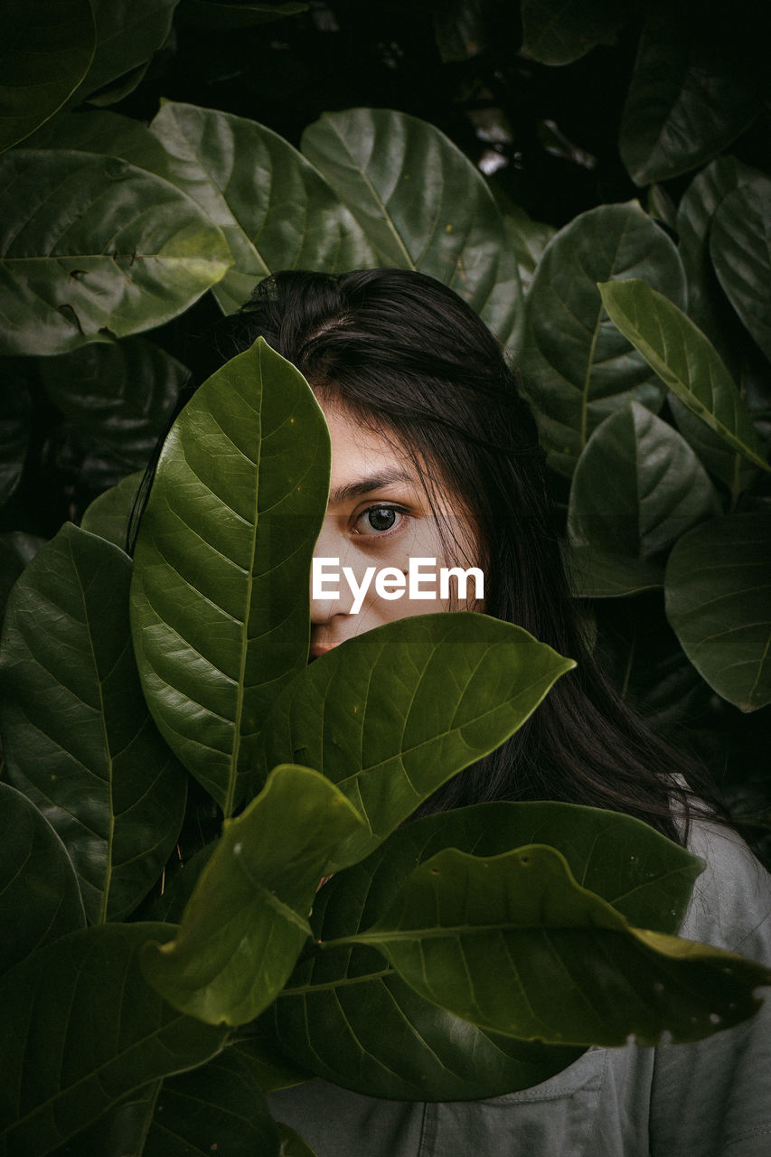 Close-up portrait of young woman amidst leaves