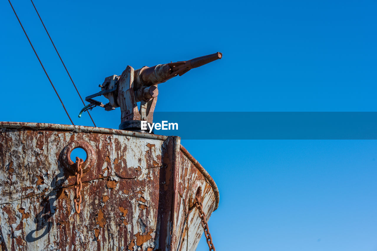 Low angle view of abandoned ship against clear blue sky