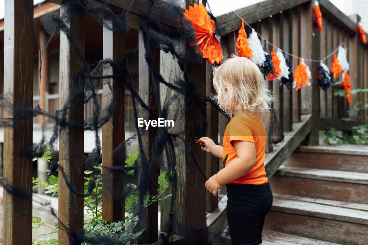 rear view of young woman standing by fence