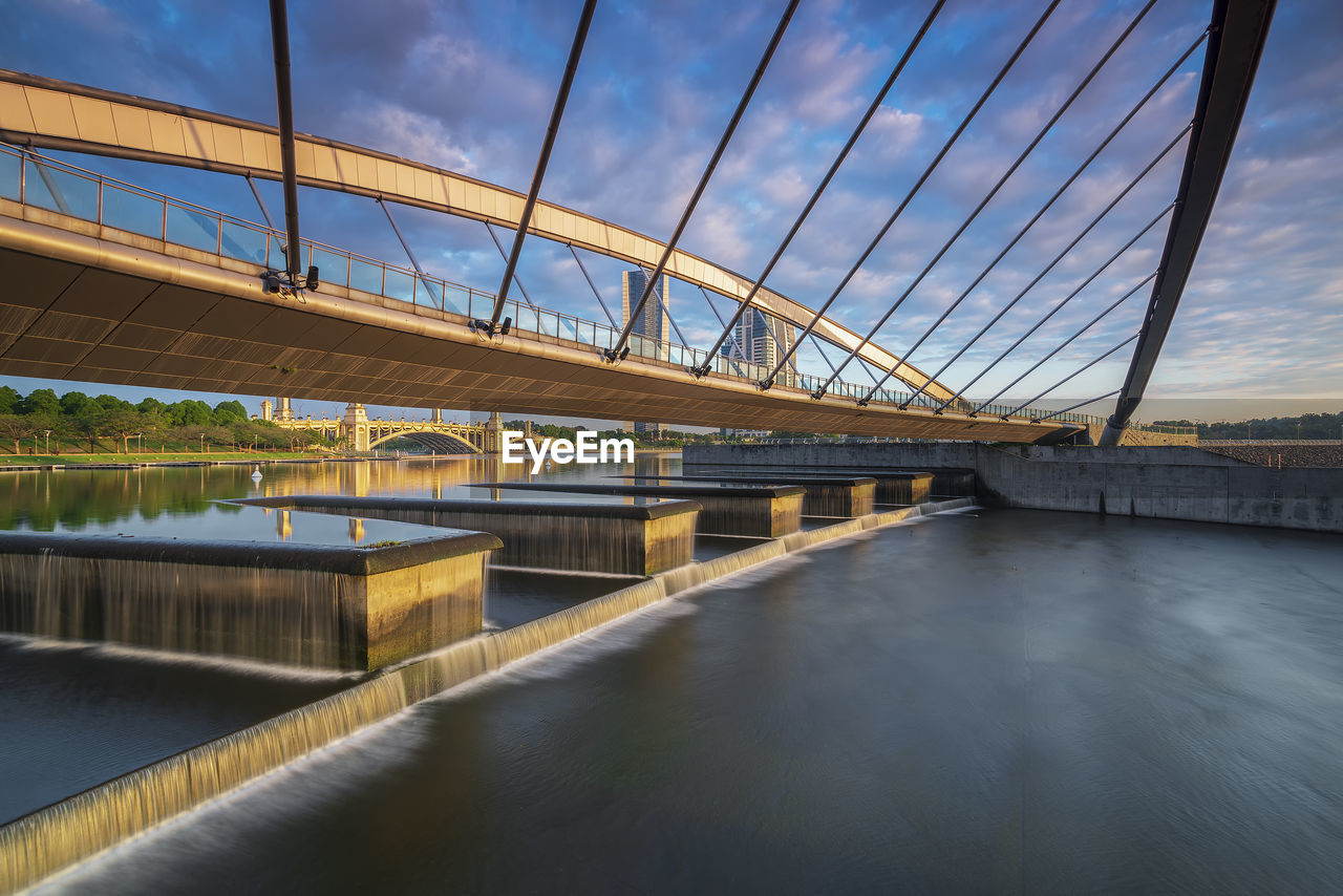 Bridge over river against cloudy sky