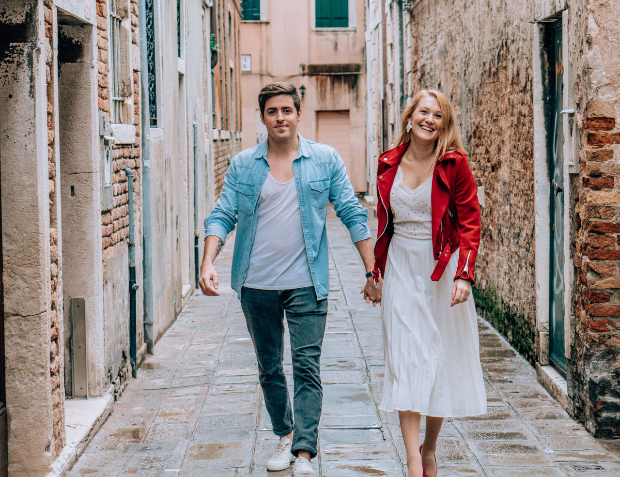 Portrait of couple holding hands while walking in alley