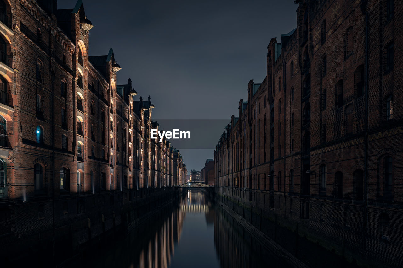 Canal amidst buildings against sky at dusk