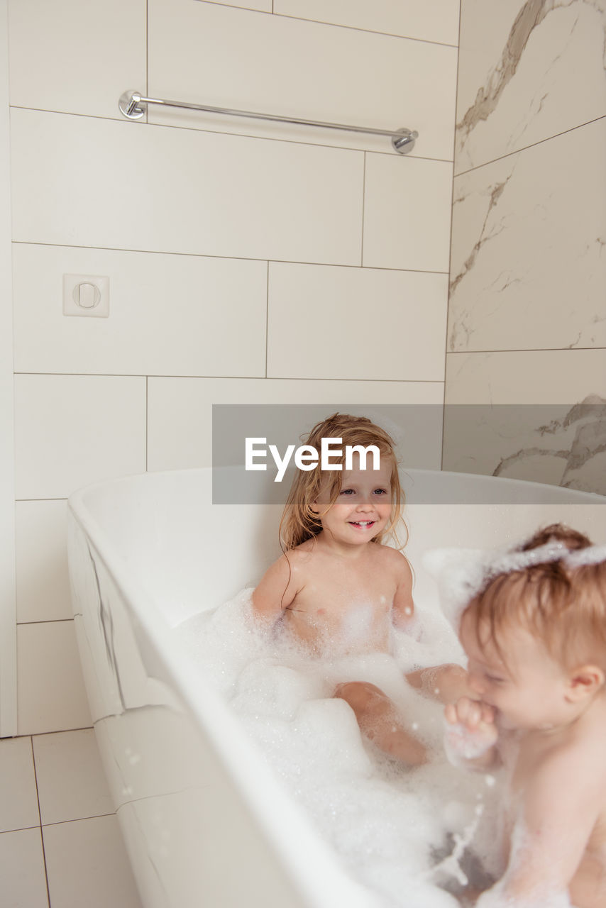 Little brother and sister bathing in a foam bath