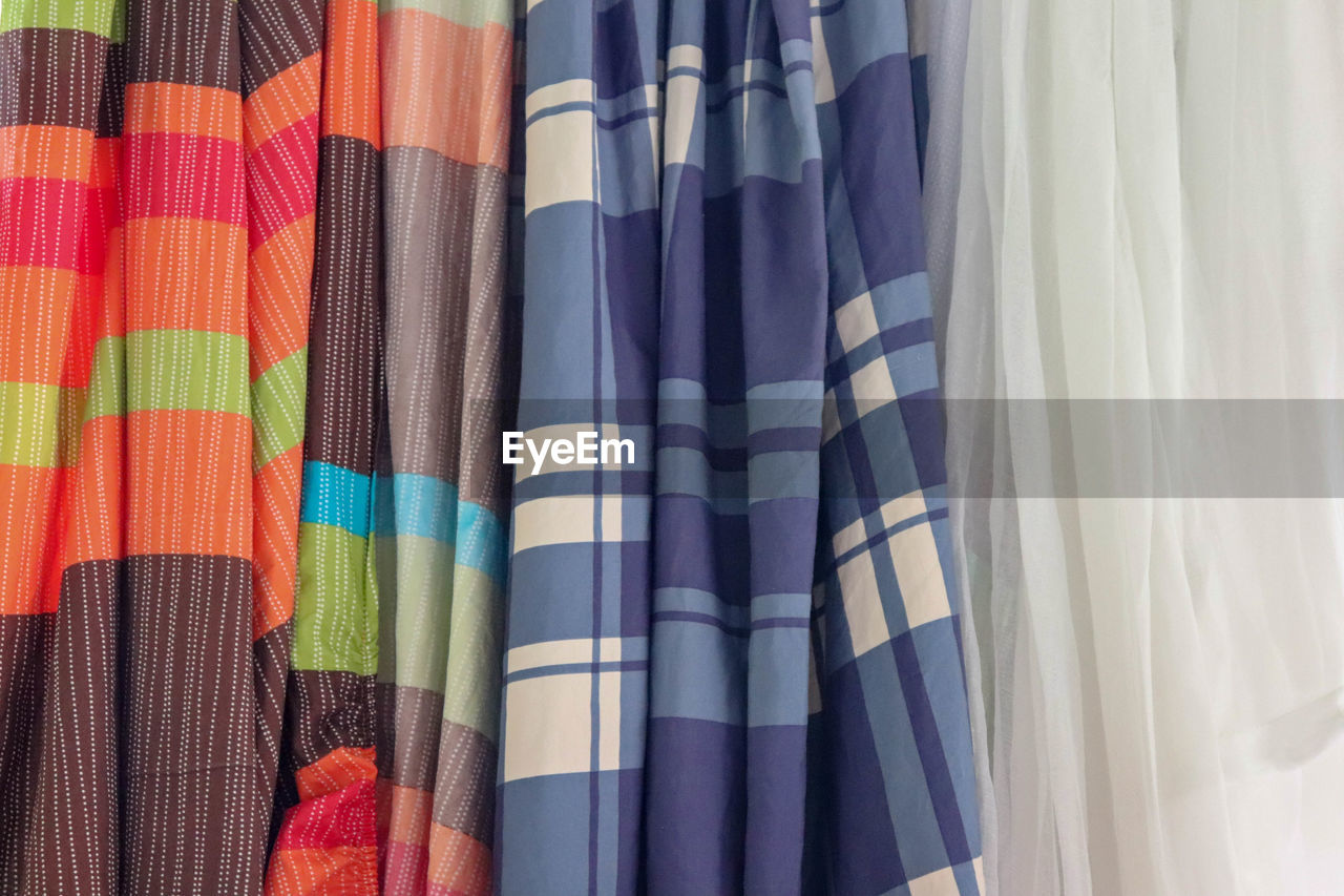 FULL FRAME SHOT OF MULTI COLORED CURTAIN HANGING IN SHELF