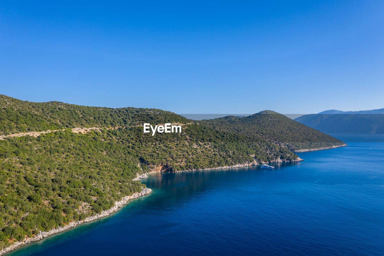 Scenic view of sea and mountains against clear blue sky