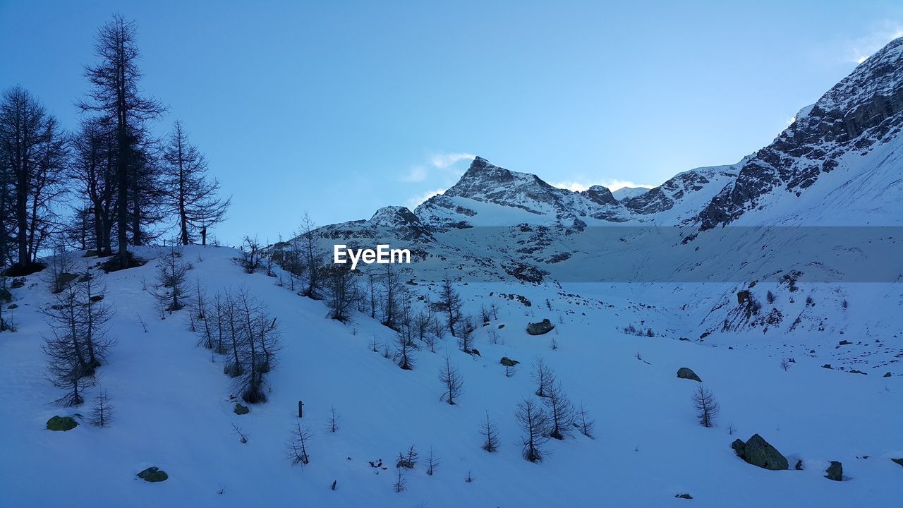 Scenic view of snow covered mountains against clear blue sky