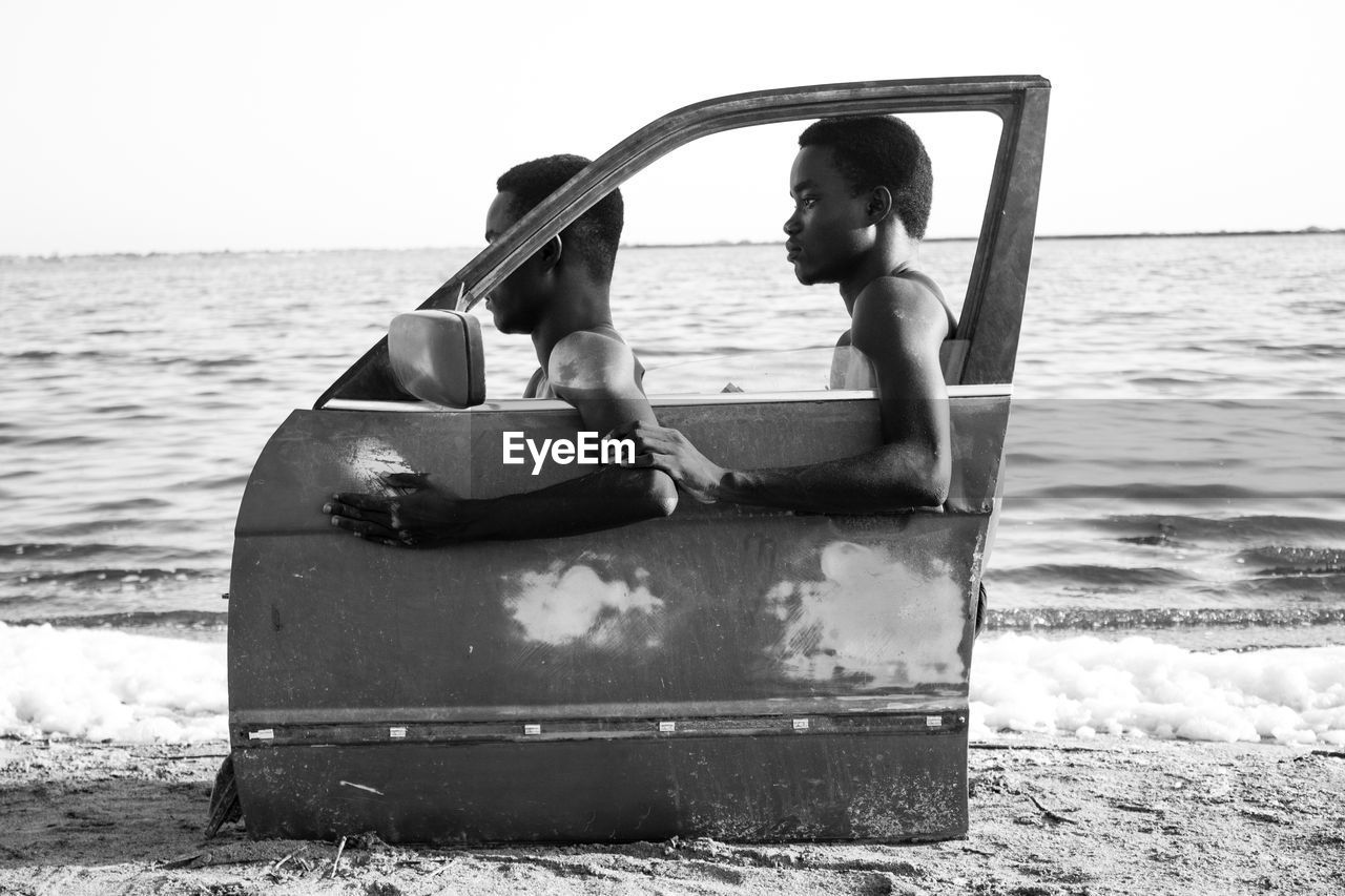 MEN SITTING ON SHORE AT BEACH