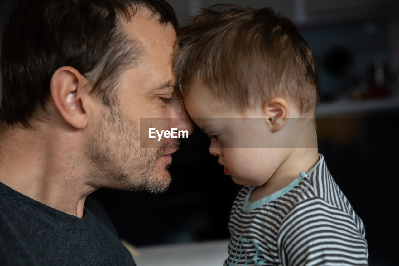 Side view of mid adult man looking at son with down syndrome