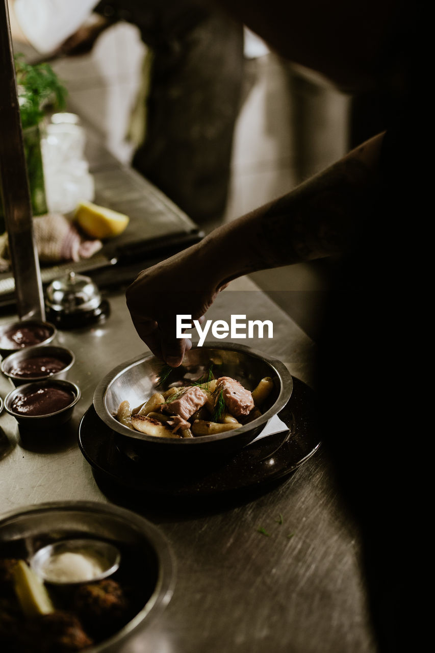 Hand garnishing food with rosemary in restaurant