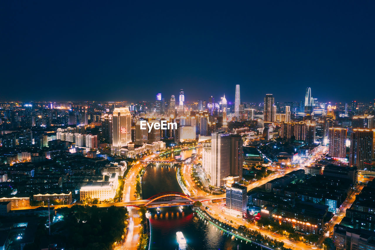 High angle view of illuminated city buildings against clear sky at night