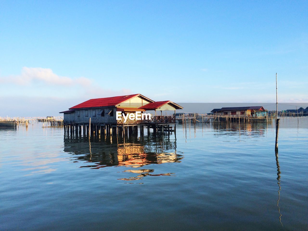 STILT HOUSE BY LAKE AGAINST SKY