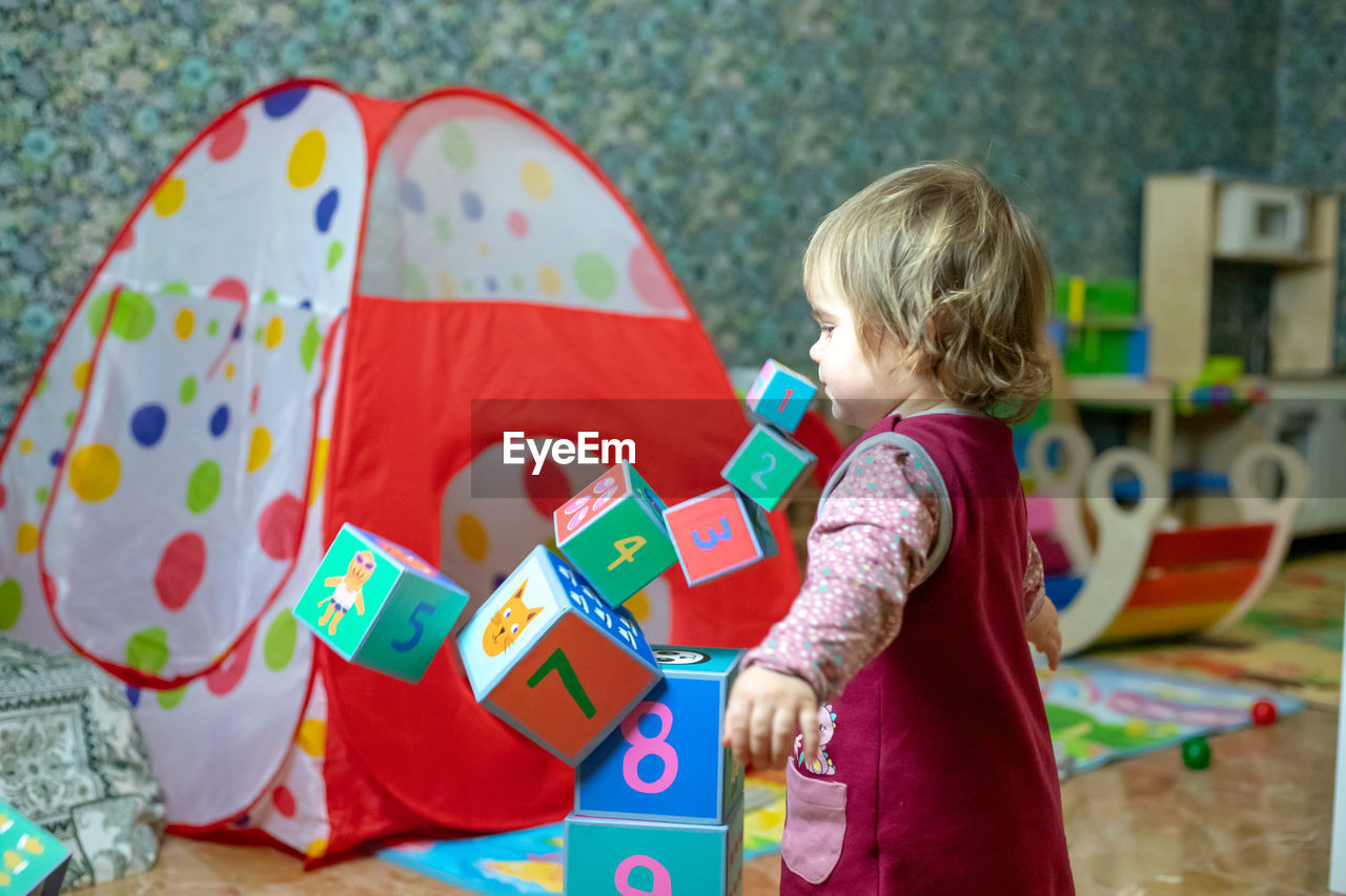Cute girl playing with toy blocks at home