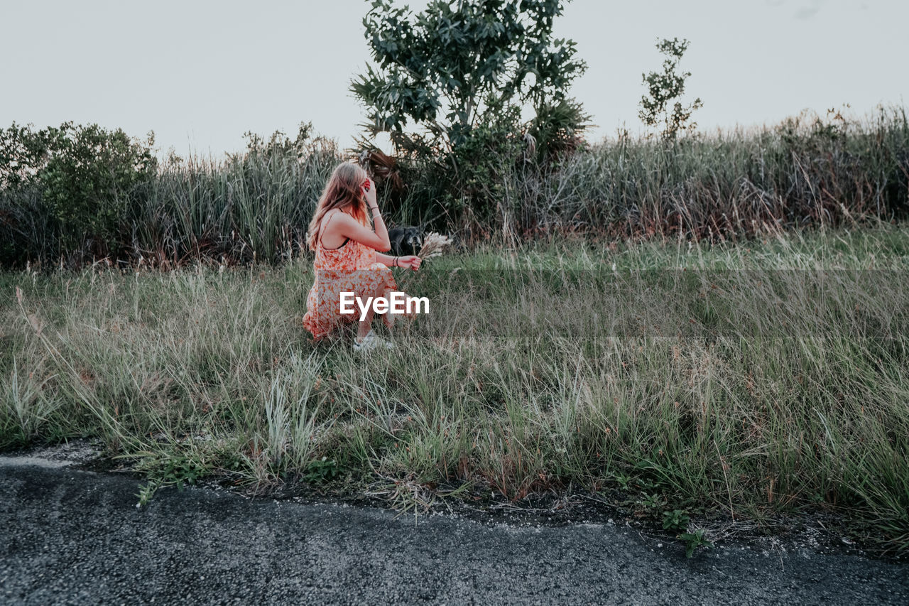 WOMAN ON FIELD AGAINST TREES