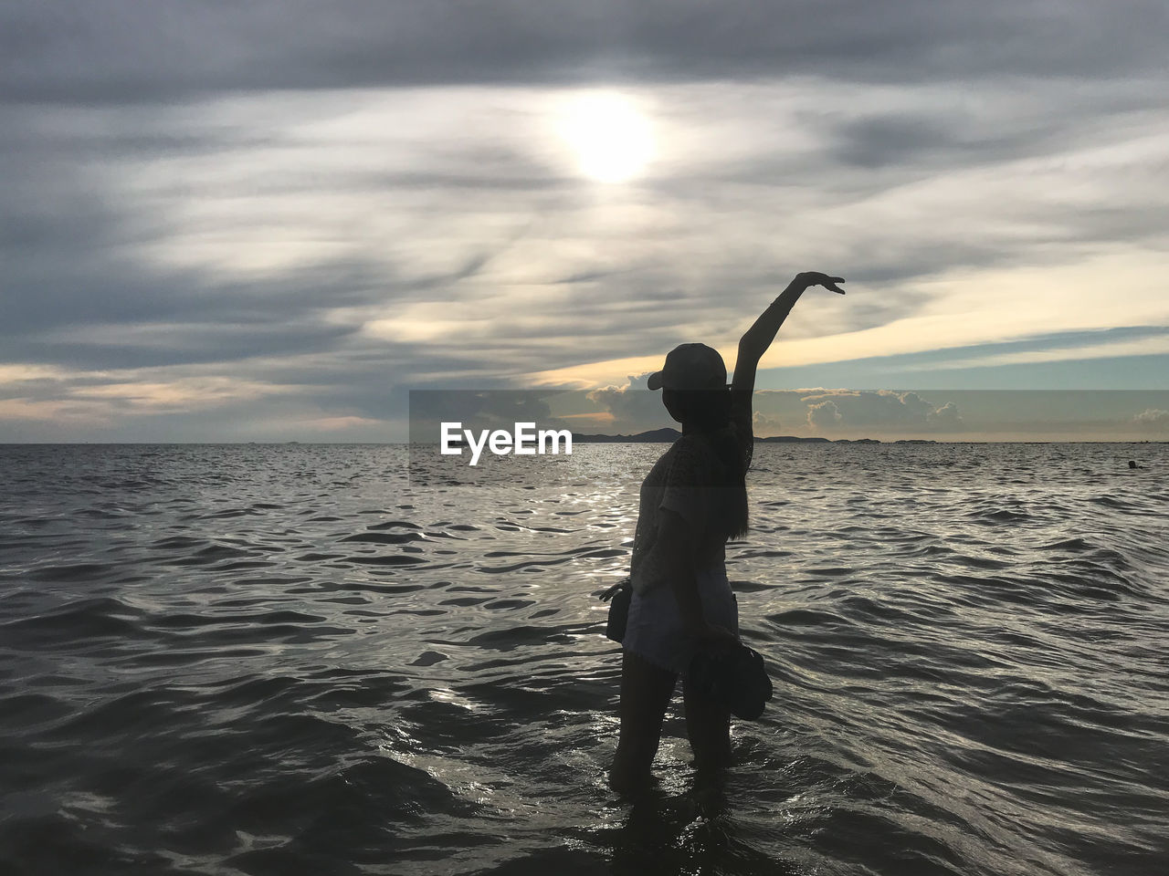 FULL LENGTH OF WOMAN STANDING AT BEACH AGAINST SKY