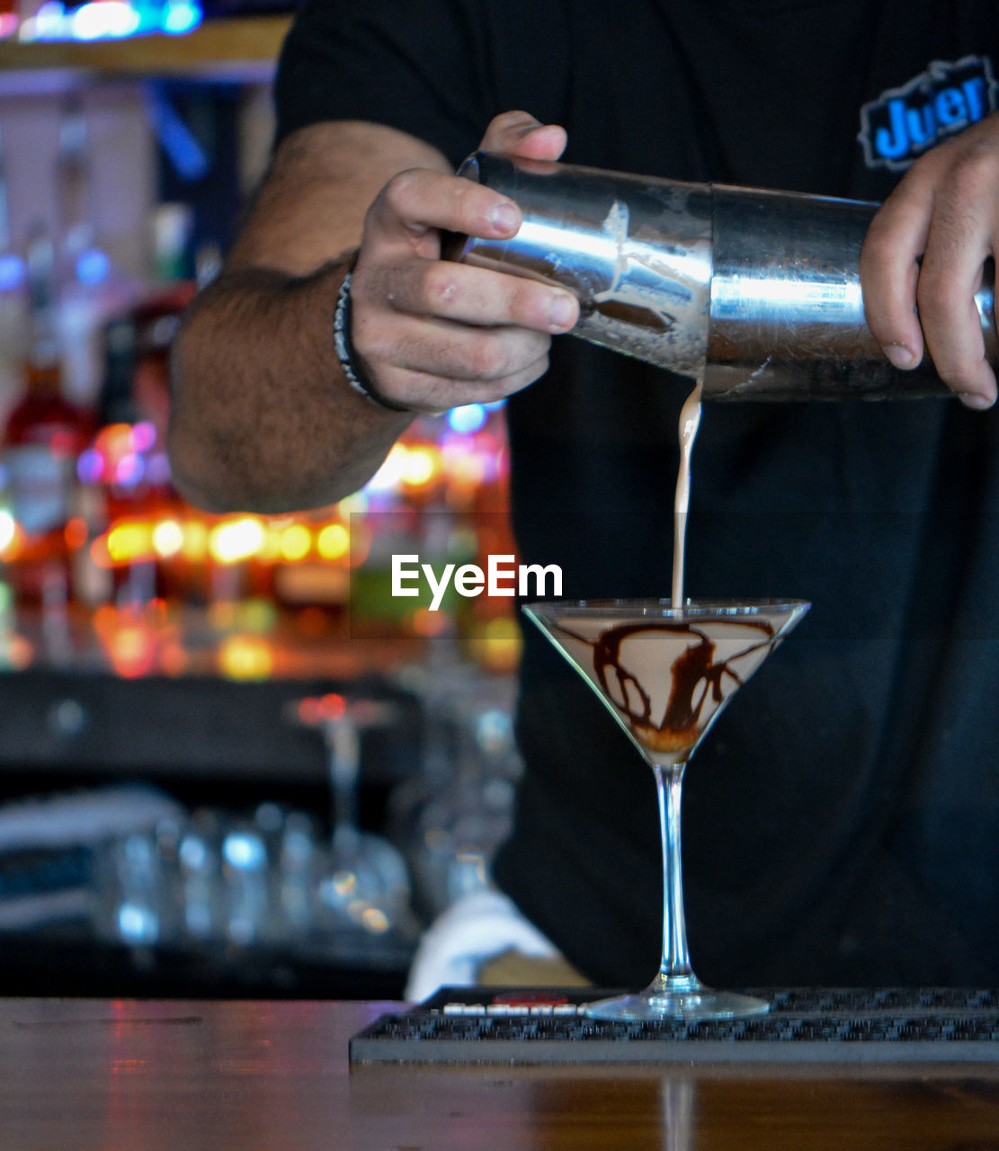 Midsection of man pouring drink in glass on table