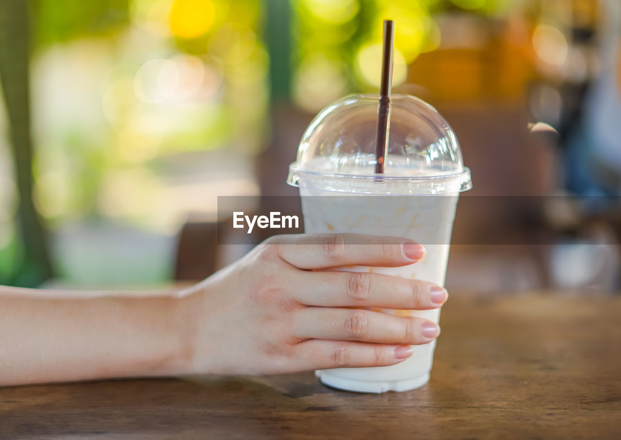 CLOSE-UP OF HAND HOLDING ICE CREAM WITH GLASS