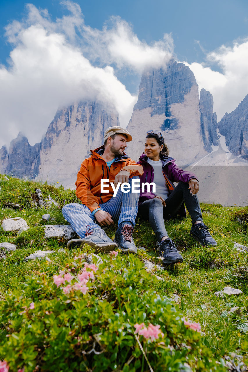 FULL LENGTH OF COUPLE SITTING ON MOUNTAIN